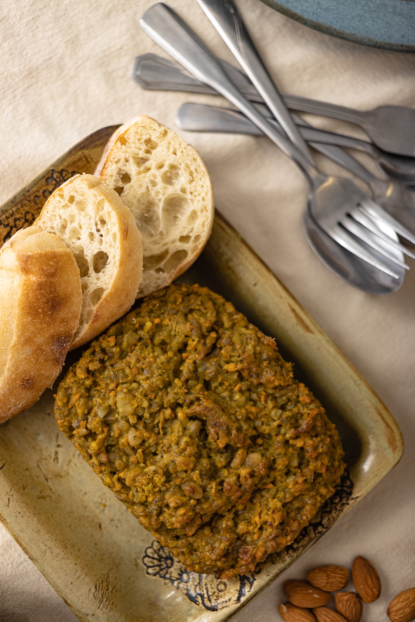 Une assiette de végé pâté aux patates douces, du pain de blé et des amandes.