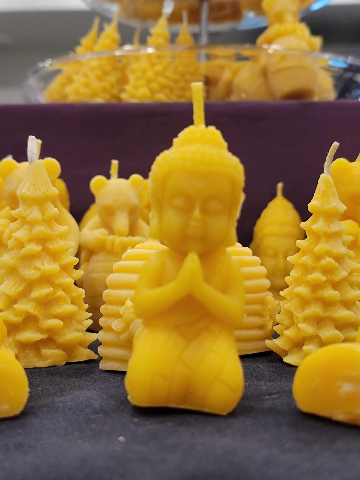 Une chandelle jaune en forme de bouddah agenouillé devant plusieurs autres modèles de chandelles jaunes