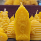 Une chandelle jaune au design de fleur de lotus  devant plusieurs autres modèles de chandelles jaunes.