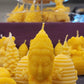 Une chandelle jaune en forme de tête de la déesse Shiva devant plusieurs autres modèles de chandelles jaunes.