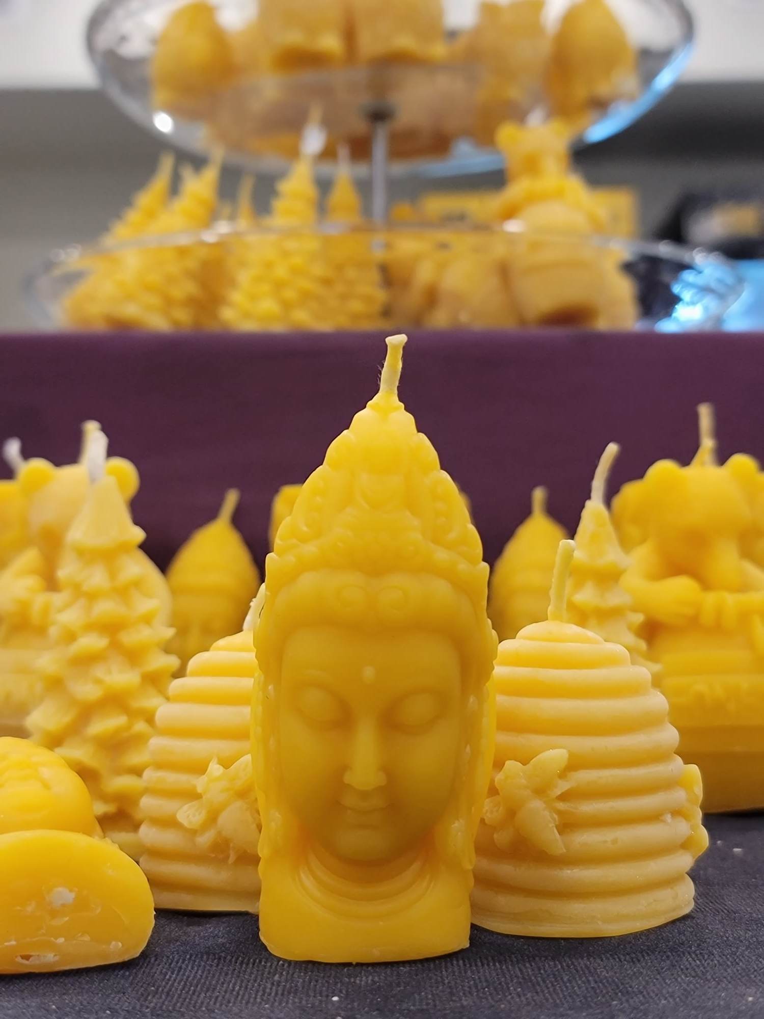 Une chandelle jaune en forme de tête de la déesse Shiva devant plusieurs autres modèles de chandelles jaunes.