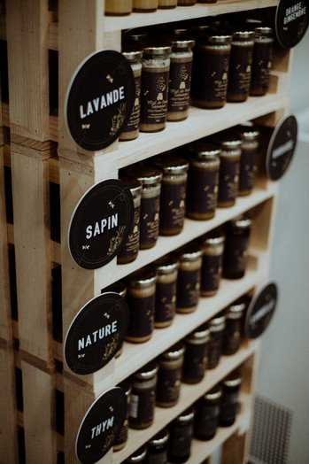 Étalage de pots de miels et aromiel avec des étiquettes mentionnant les saveurs de lavande, sapin, nature et thym.