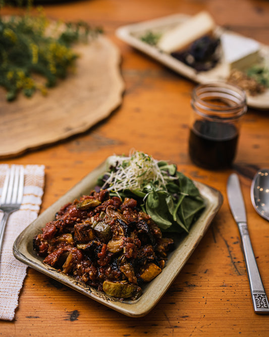 Une assiette de ratatouille et de salade verte sur une table en bois. 