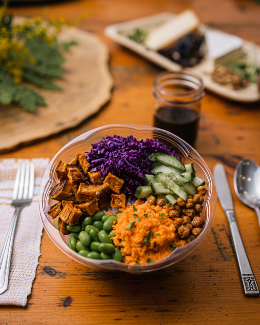 Une assiette de salade composée de riz, édame et patates douces sur une table en bois