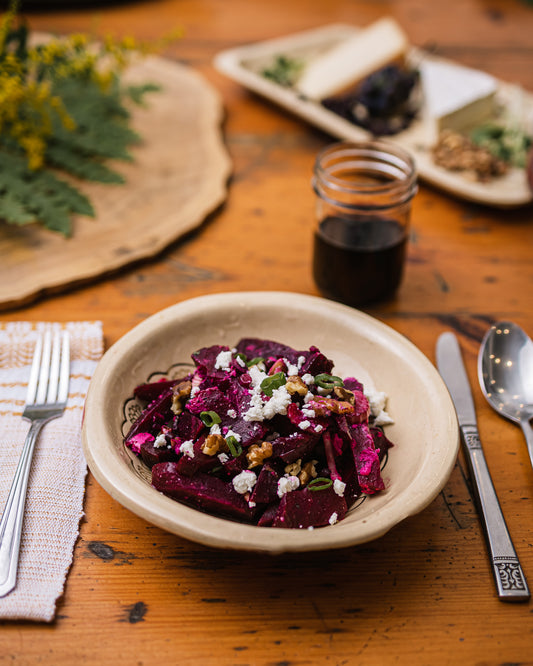 Une assiette de salade de betteraves, grenobles et chèvre sur une table en bois. 
